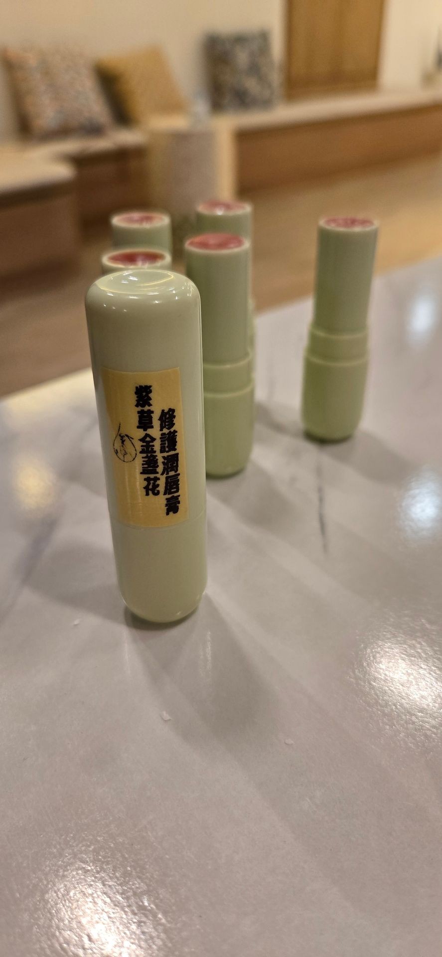 Close-up of green cylindrical containers with Chinese characters on a label, arranged on a reflective surface.